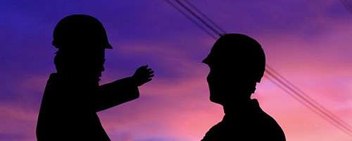 two workers talking against sunset