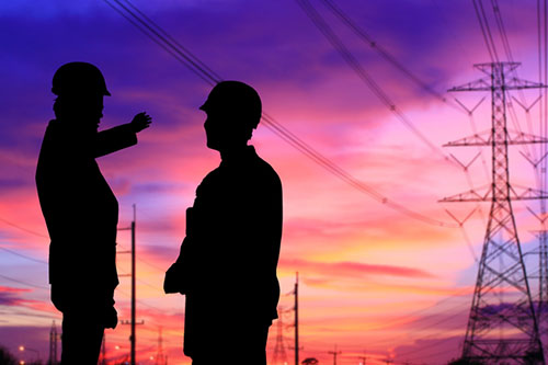 two workers and power lines against sunset